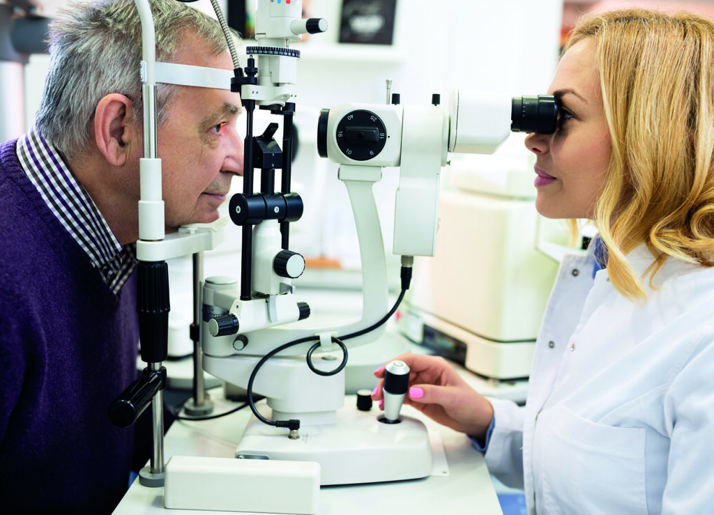 Une femme médecin ophtalmologiste examine les yeux d'un homme âgé dans une clinique ophtalmologique.